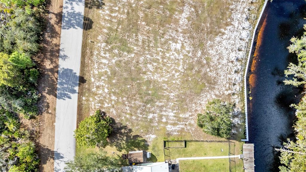 An aerial view shows a vacant lot bordered by a road, a canal, and trees — 1100 SYCAMORE STREET, LAKE PLACID, FL