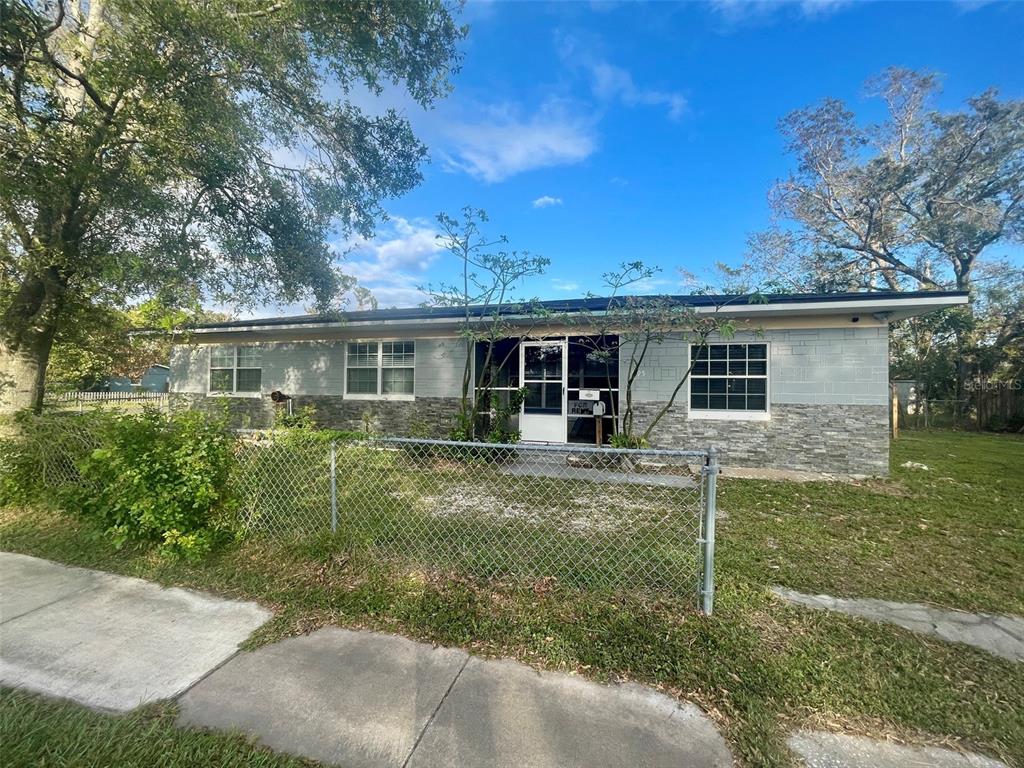 A single-story house with a gray block exterior, stone veneer base, and a chain-link fence — 3995 40TH STREET N, ST PETERSBURG, FL