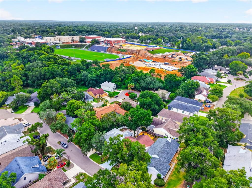 An aerial view shows a residential neighborhood adjacent to a school with an active construction site — 57 TOWNHILL DRIVE, EUSTIS, FL