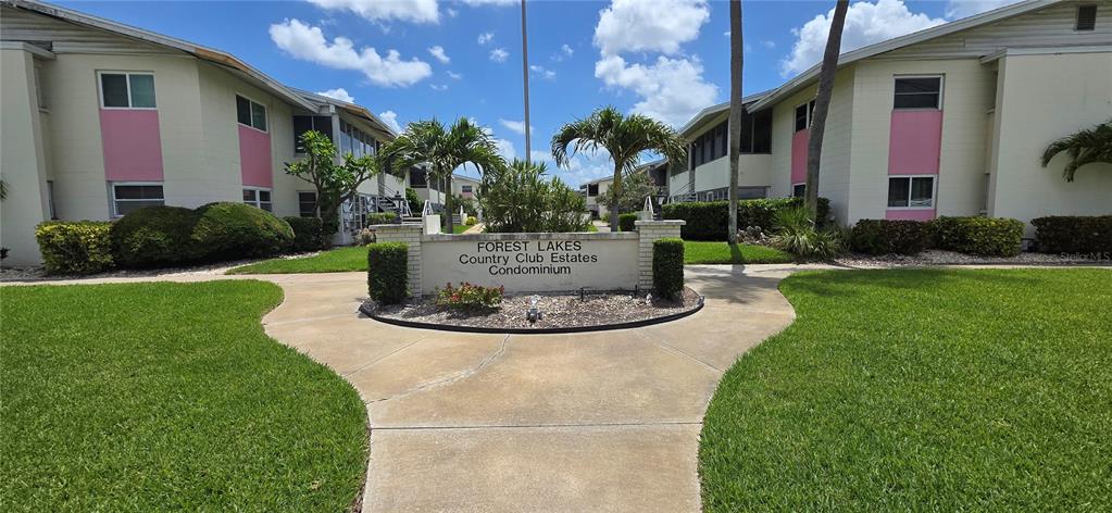 A concrete walkway leads to a sign for Forest Lakes Country Club Estates between buildings — 2507 BENEVA ROAD UNIT 5, SARASOTA, FL