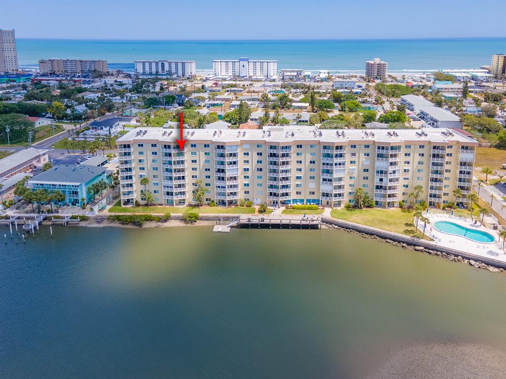 An aerial view shows a multi-story waterfront condominium building with a pool and dock — 3606 S PENINSULA DRIVE UNIT 703, PORT ORANGE, FL