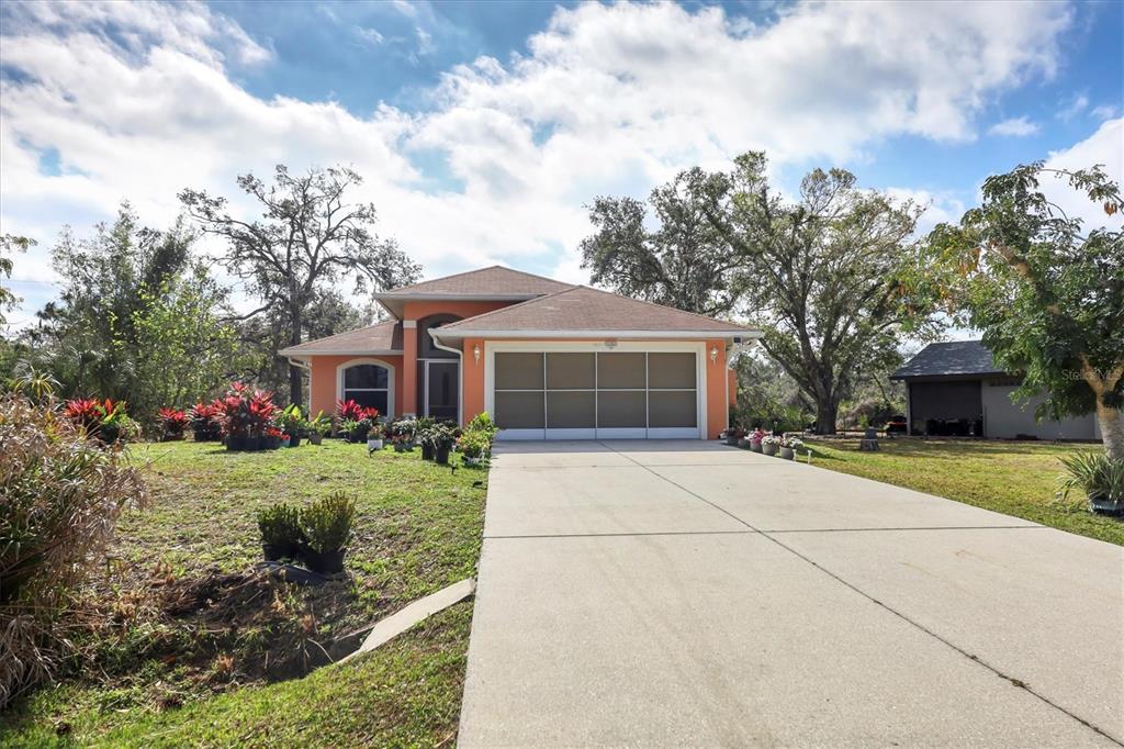 A single-story house with an orange exterior, a two-car garage, and a concrete driveway — 11907 DE LEON DRIVE, NORTH PORT, FL