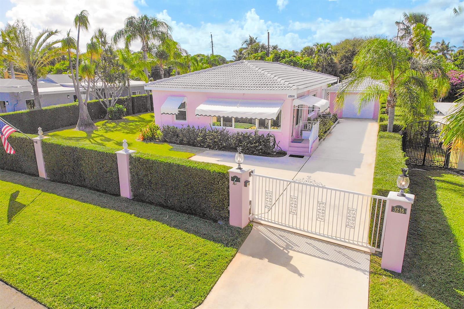 A pink house with a white roof and awnings sits behind a gated driveway — 3216 Karen Drive, Delray Beach FL 33483, DELRAY BEACH, FL