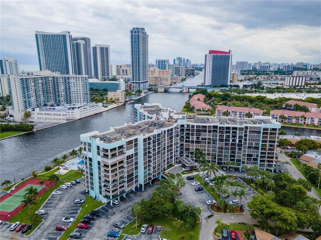 An aerial view shows a large apartment complex situated along a canal in a city — 200 Leslie Drive # 1128, Hallandale Beach FL 33009, HALLANDALE BEACH, FL