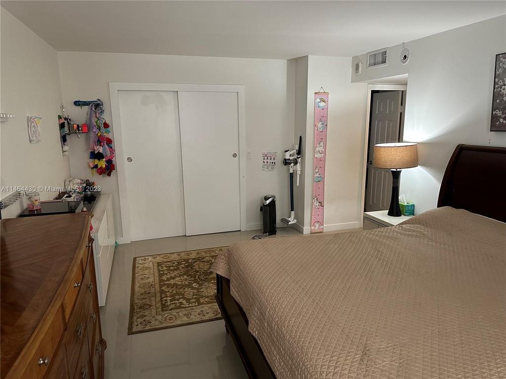 A bedroom features a bed, a dresser, a closet with sliding doors, and tiled flooring — 200 Leslie Drive # 1128, Hallandale Beach FL 33009, HALLANDALE BEACH, FL