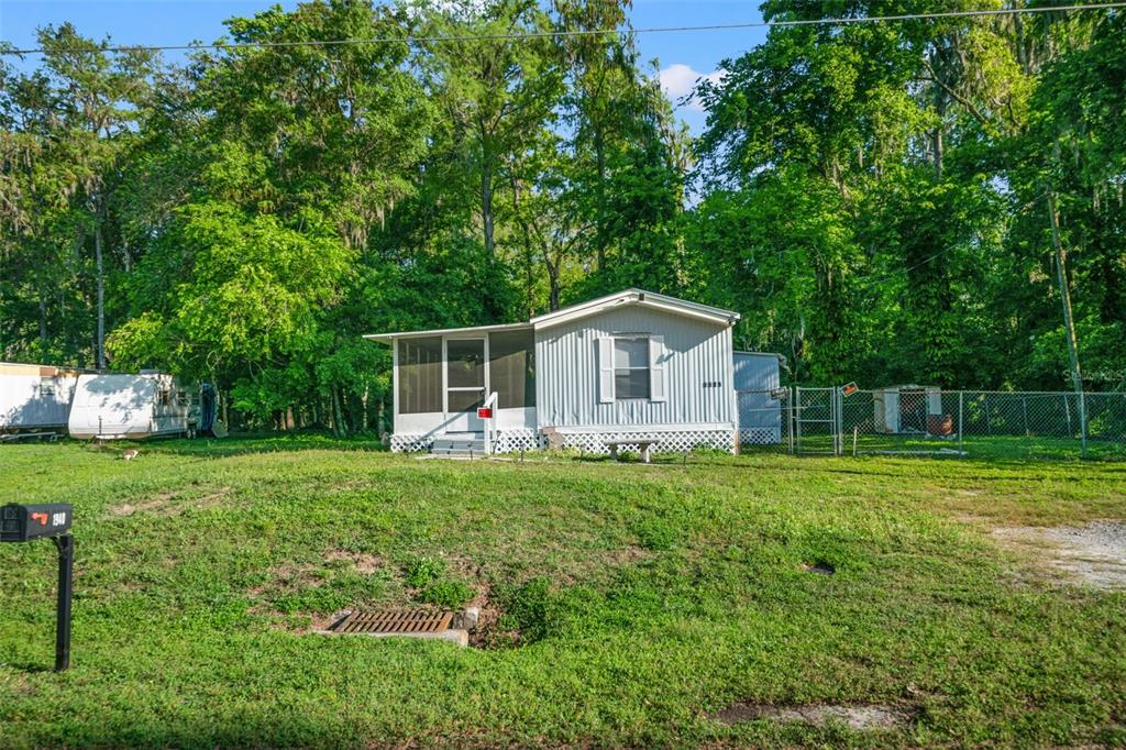 A single-story mobile home with a screened porch sits on a grassy lot with trees — 1940 CR 428, LAKE PANASOFFKEE, FL