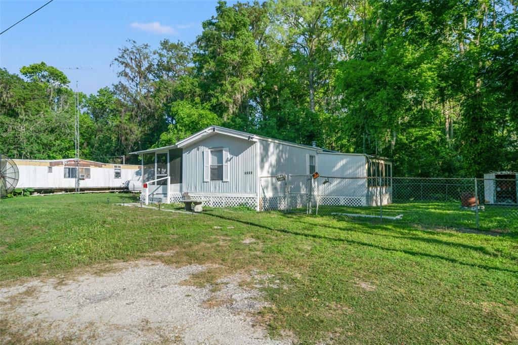 A light-colored mobile home with a screened porch sits on a grassy lot with trees — 1940 CR 428, LAKE PANASOFFKEE, FL