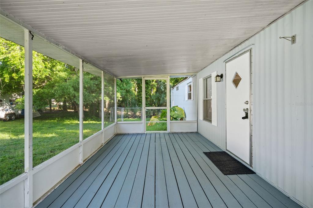 A screened-in porch features a painted wooden floor, white siding, and a single entry door — 1940 CR 428, LAKE PANASOFFKEE, FL