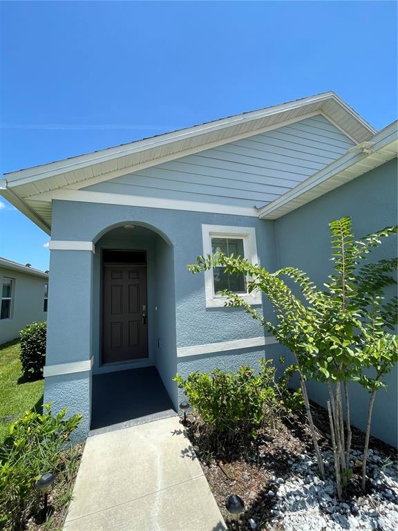 The exterior of a light blue house features a covered entryway with a dark door — 1617 HEART BAR ROAD, KISSIMMEE, FL