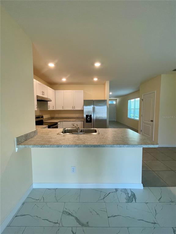 A kitchen features white cabinets, stainless steel appliances, and a breakfast bar with laminate countertops — 1617 HEART BAR ROAD, KISSIMMEE, FL