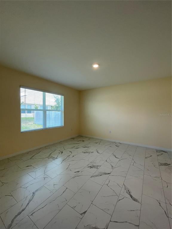 An empty room with light yellow walls and white marble-patterned tile flooring — 1617 HEART BAR ROAD, KISSIMMEE, FL