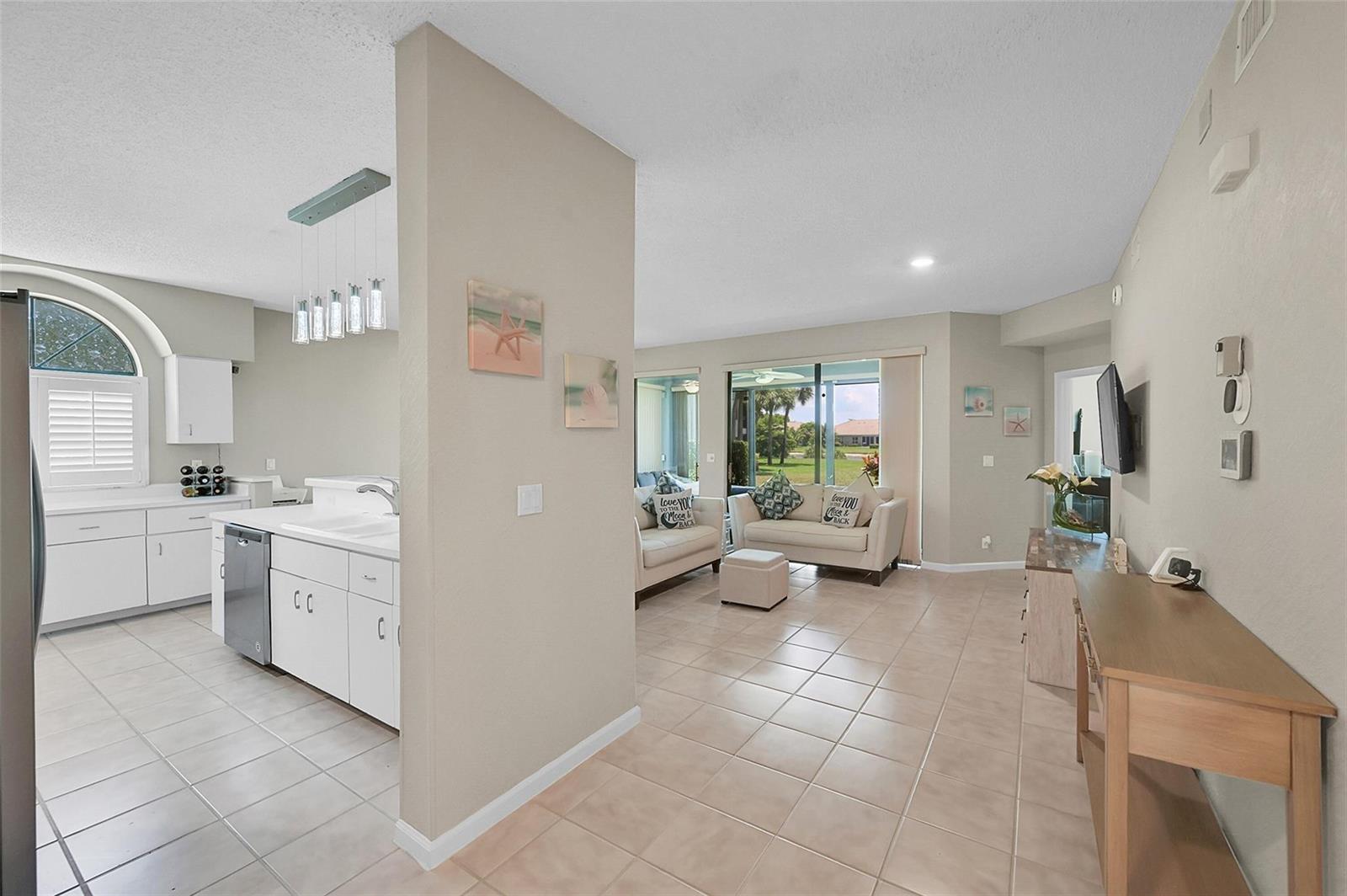 A kitchen with white cabinets and a tile floor opens into a bright living area — 8049 Aberdeen Drive # 101, Boynton Beach FL 33472, BOYNTON BEACH, FL