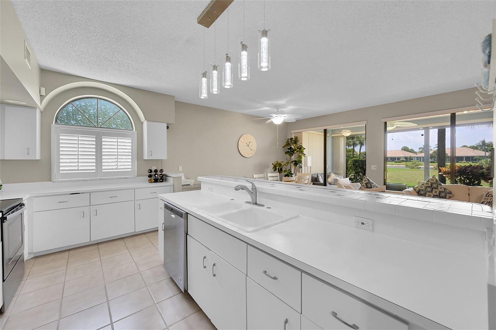 A white kitchen features a breakfast bar, tile countertops, and a view of the outdoors — 8049 Aberdeen Drive # 101, Boynton Beach FL 33472, BOYNTON BEACH, FL