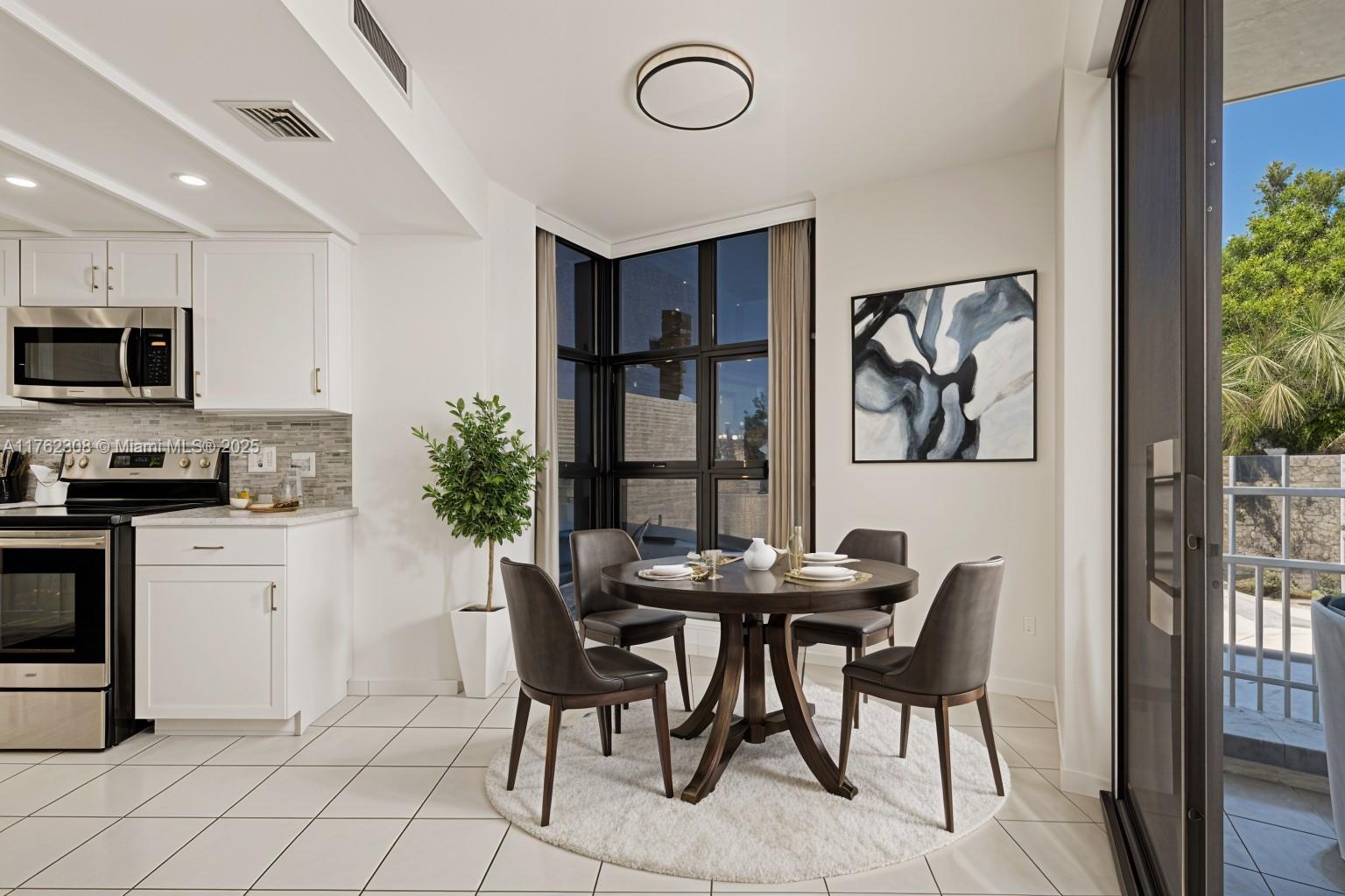 A dining area with a round table and chairs sits adjacent to a white kitchen — 4000 Towerside Ter # 302, Miami FL 33138, MIAMI, FL