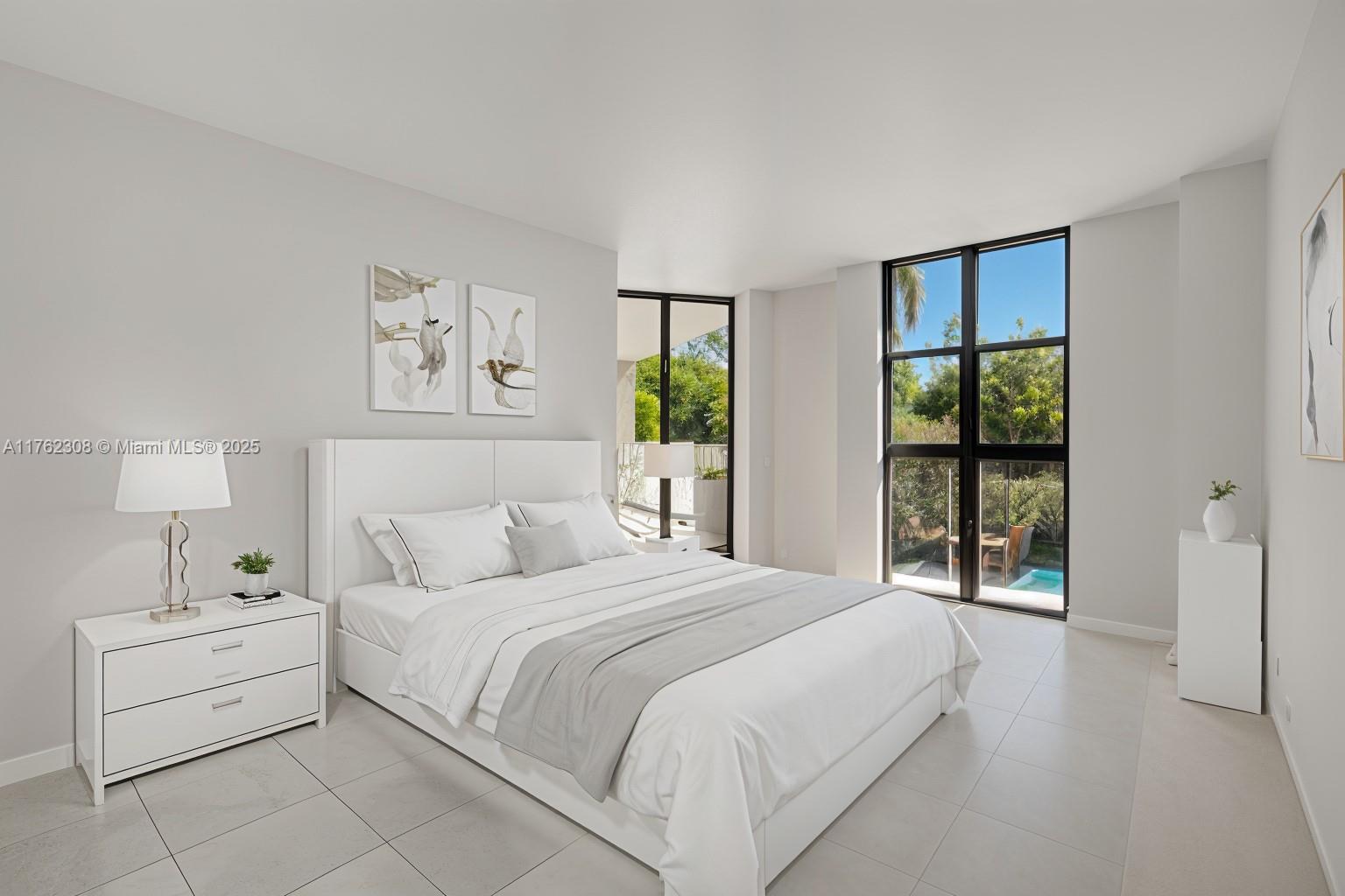 A modern bedroom features a white bed, tiled floors, and large windows overlooking a pool area — 4000 Towerside Ter # 302, Miami FL 33138, MIAMI, FL
