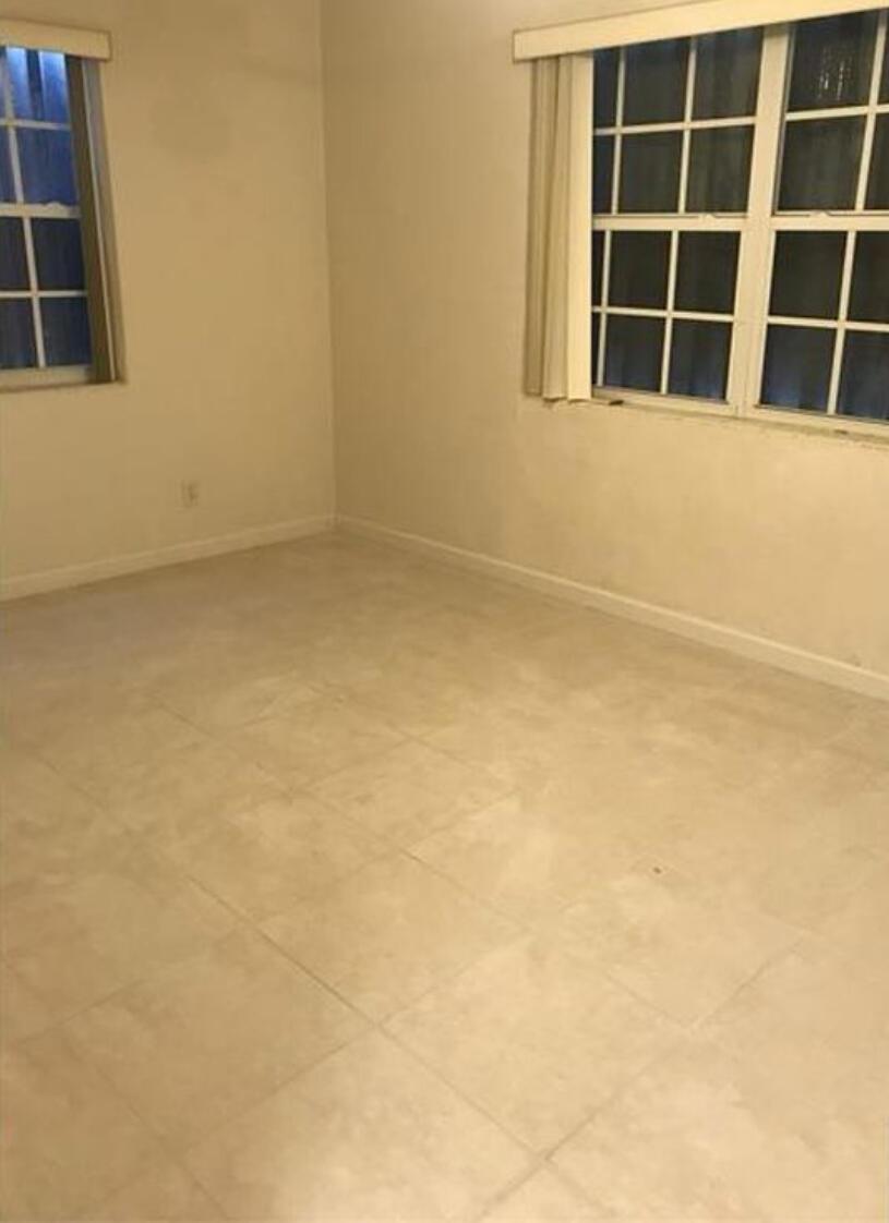 An empty room with light-colored tile flooring, white walls, and two windows with blinds — 635 48th Street, West Palm Beach FL 33407, WEST PALM BEACH, FL