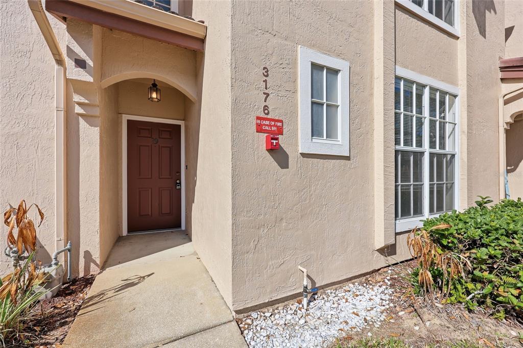 The exterior view shows a tan stucco building entrance with a brown door and walkway — 3176 TAMARIND CIRCLE UNIT 19, KISSIMMEE, FL