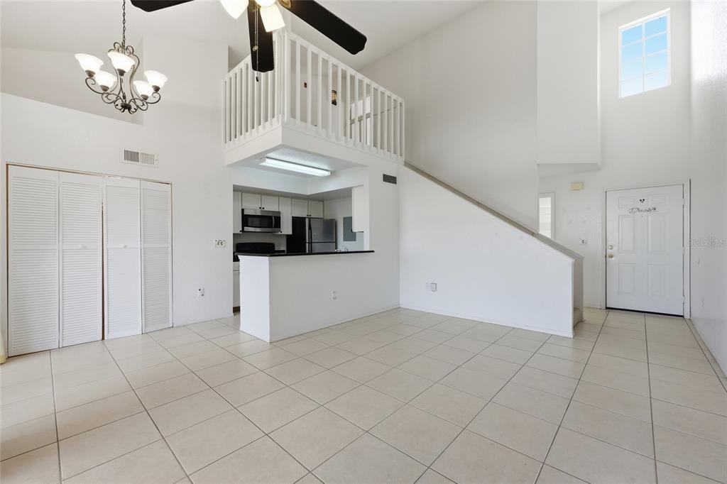 A bright living area features tile flooring, a lofted balcony, and an open kitchen — 3176 TAMARIND CIRCLE UNIT 19, KISSIMMEE, FL