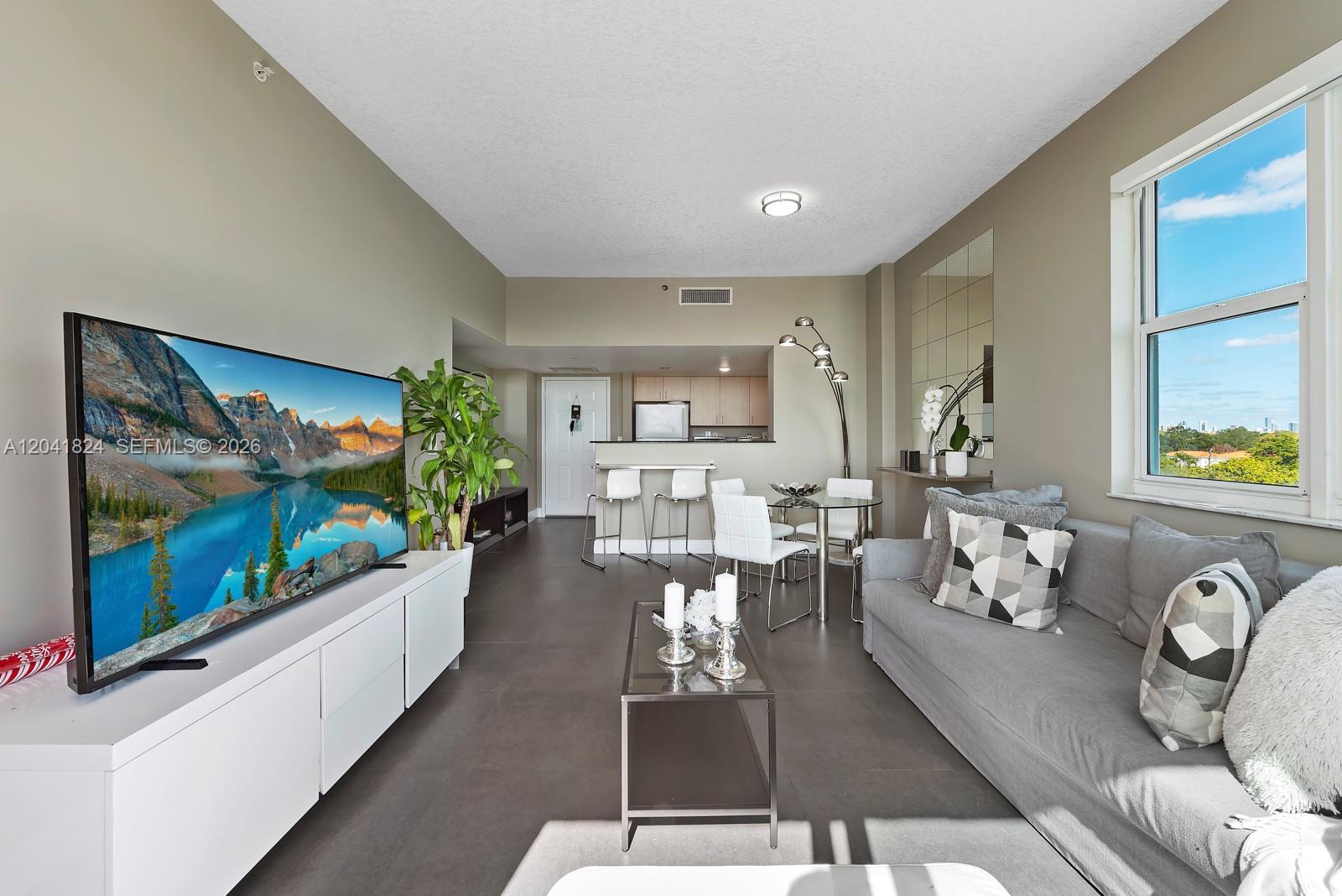 A living room features a large television, gray sofa, dining area, and kitchen with tile floors — 3000 CORAL WAY # 416, Miami FL 33145, MIAMI, FL
