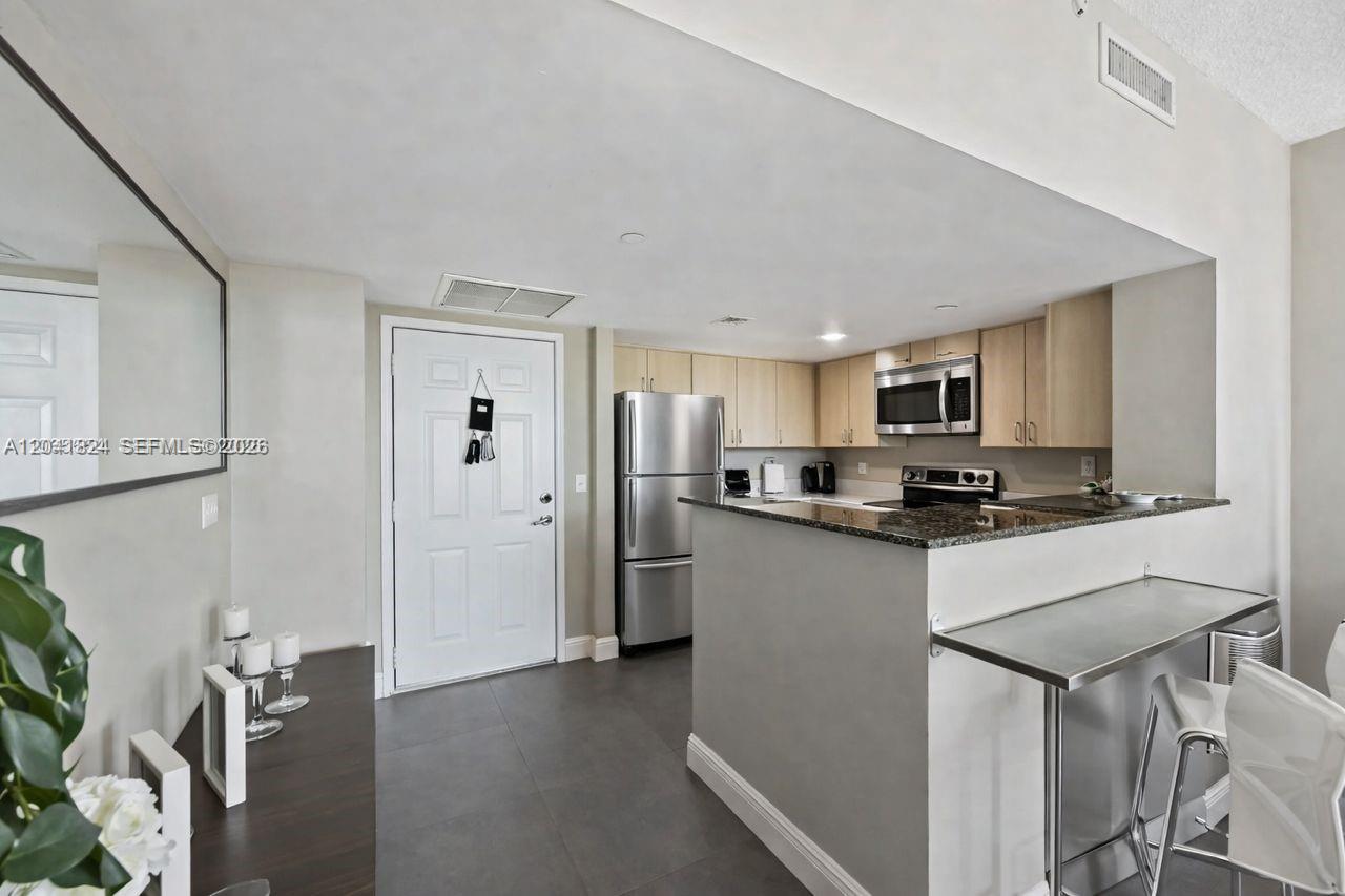 A kitchen features stainless steel appliances, light wood cabinets, and a granite-topped breakfast bar — 3000 CORAL WAY # 416, Miami FL 33145, MIAMI, FL