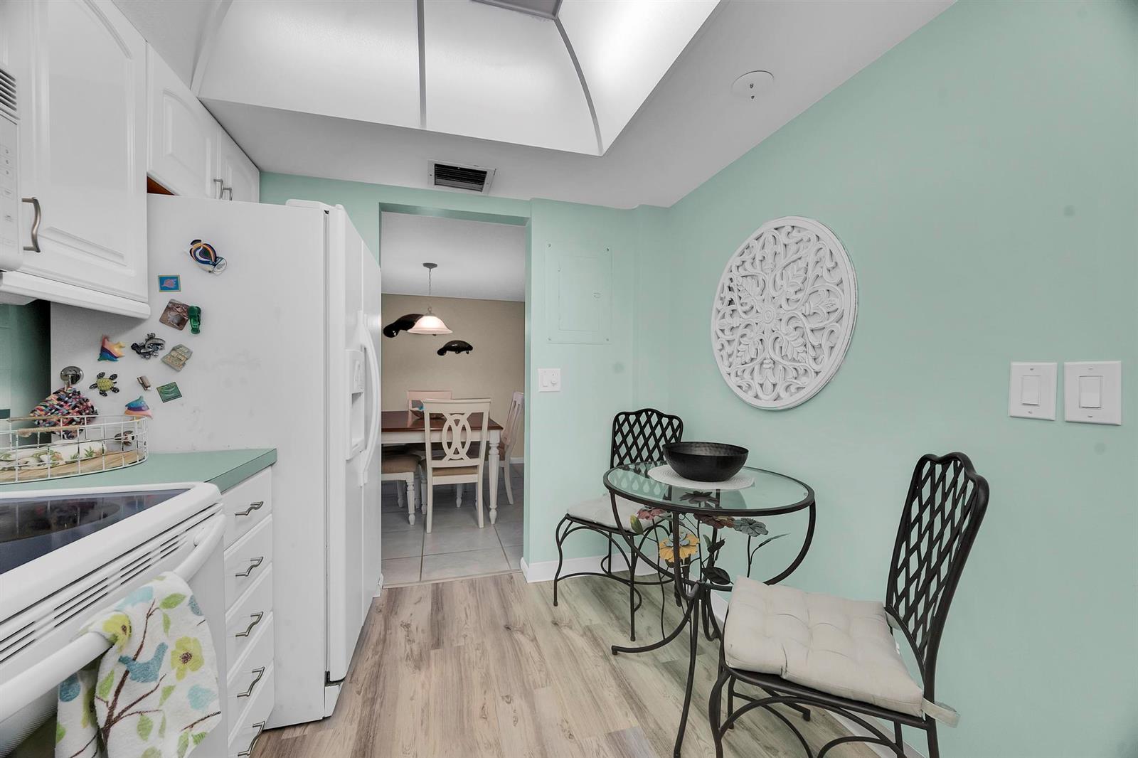 A kitchen with light green walls, white cabinets, and a small glass-topped dining table — 3492 NE Causeway Boulevard # 103, Jensen Beach FL 34957, JENSEN BEACH, FL