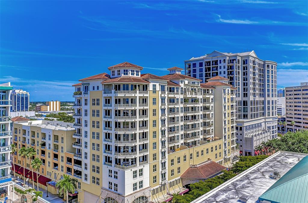 An aerial view of a multi-story apartment complex with balconies and a blue sky — 100 CENTRAL AVENUE UNIT H716, SARASOTA, FL