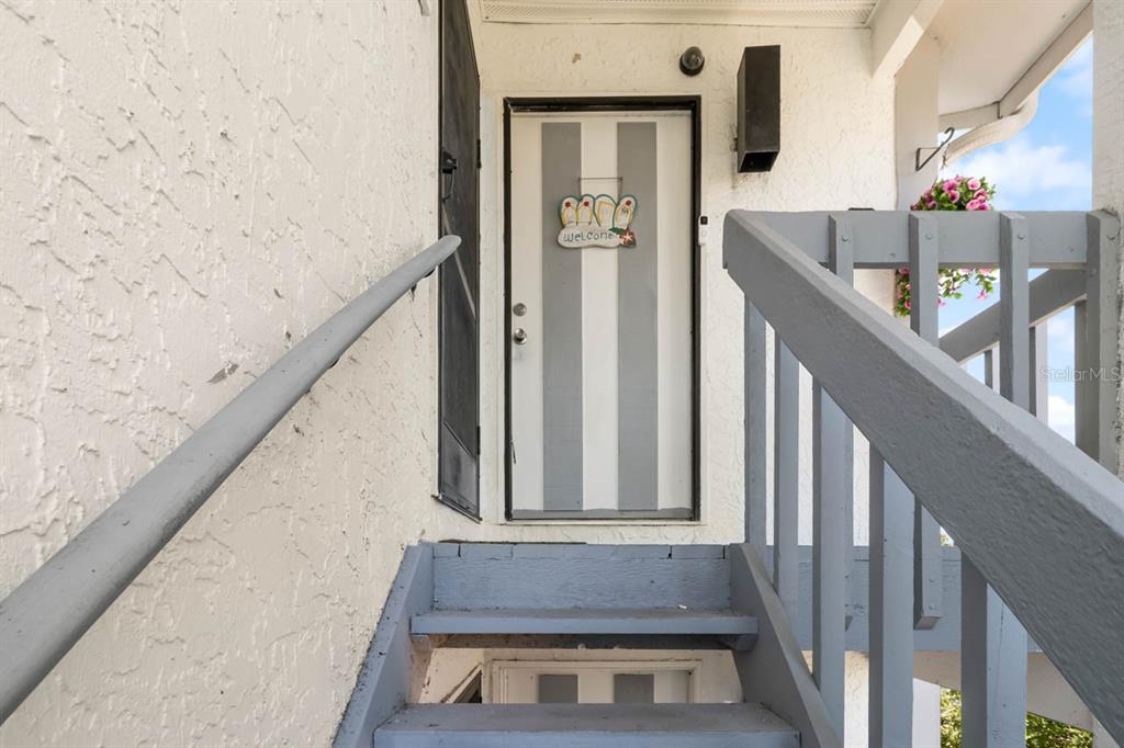 An exterior view shows a set of stairs leading to a striped front door — 609 LIVELY DRIVE UNIT B, SUN CITY CENTER, FL