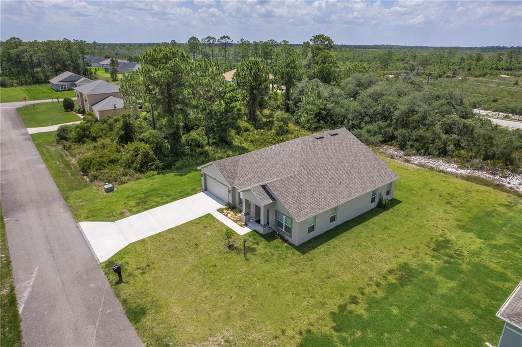 An aerial view shows a single-story house with a gray roof and a concrete driveway — 5236 SUE DRIVE, SEBRING, FL