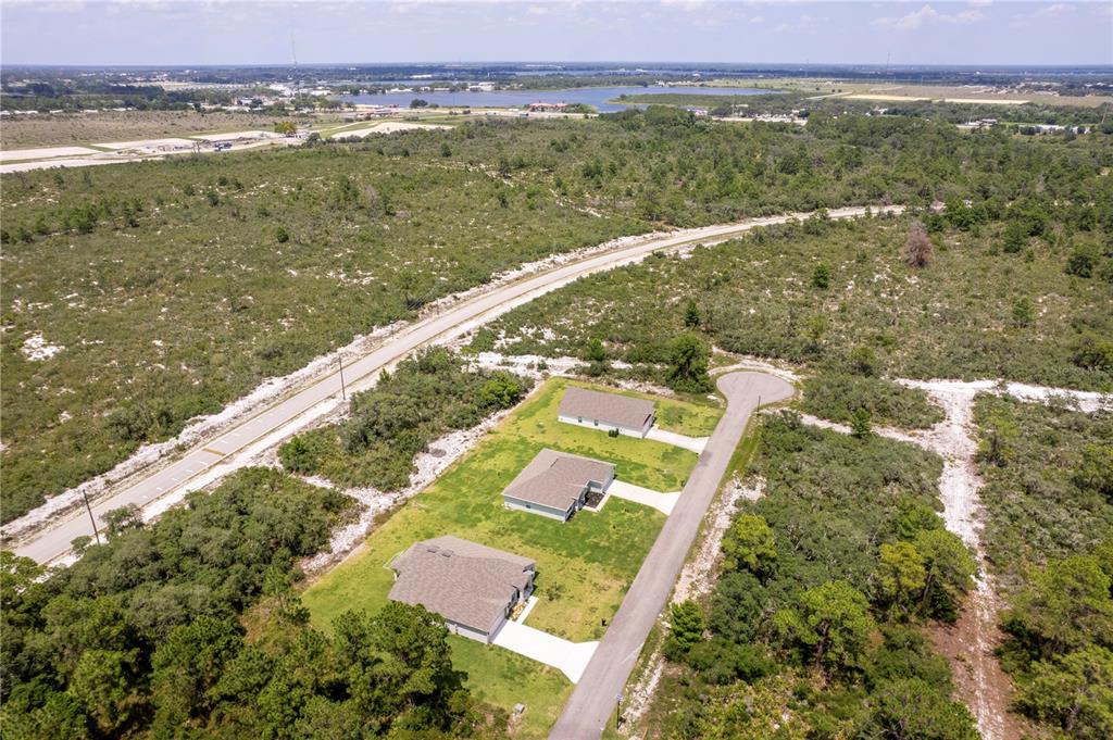 An aerial view shows three houses situated on a cul-de-sac surrounded by undeveloped wooded land — 5236 SUE DRIVE, SEBRING, FL