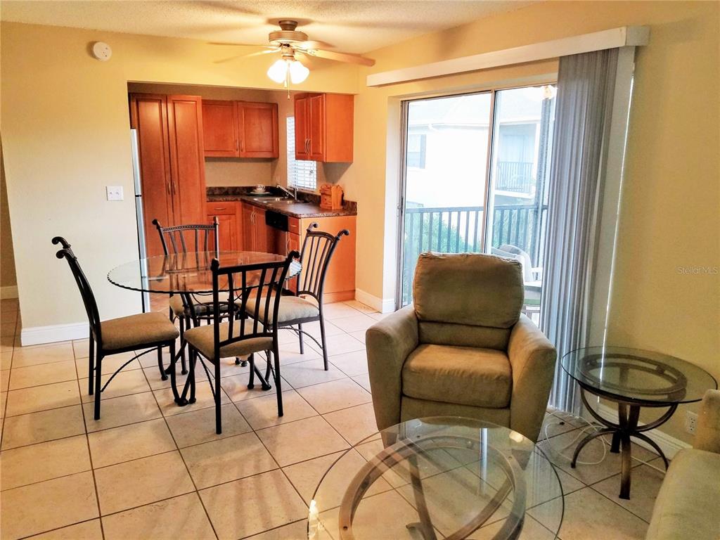A dining area with a glass table and chairs sits adjacent to a kitchen — 13125 WILCOX ROAD UNIT 7203, LARGO, FL