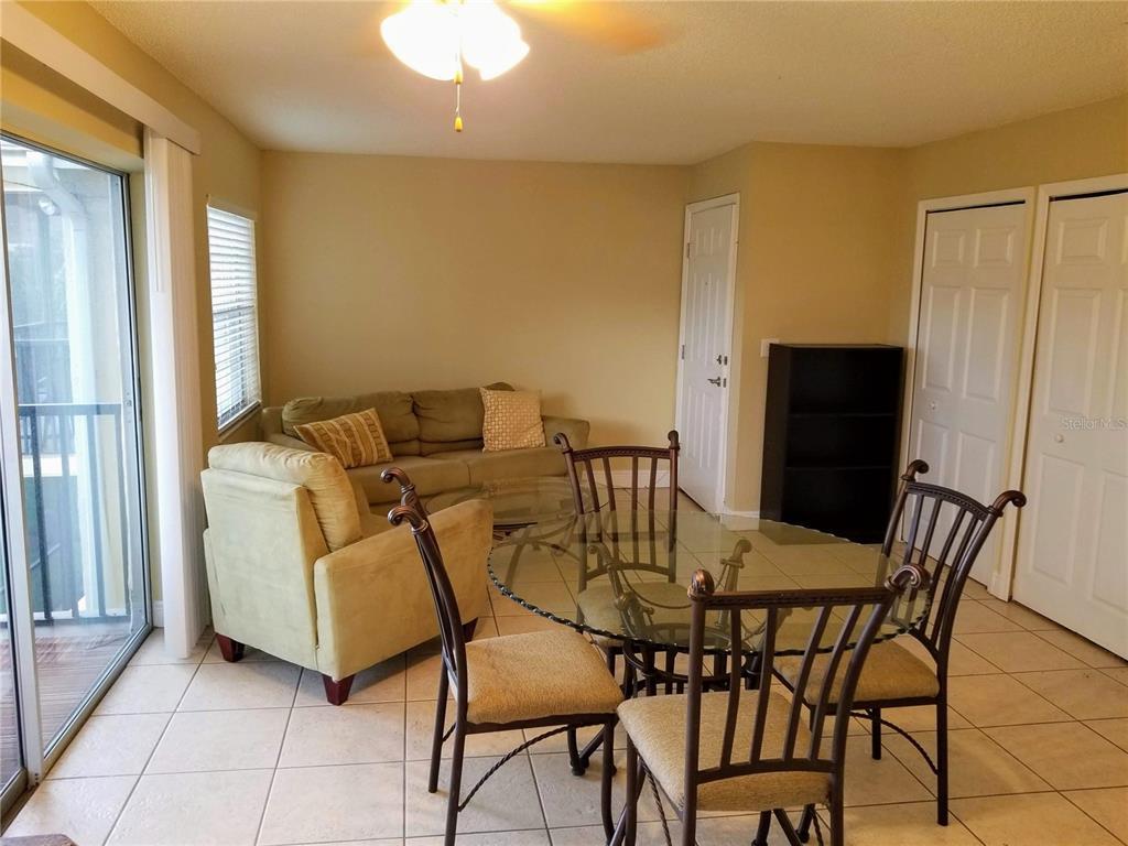 A living and dining area with tile floors, a glass table, and a sofa — 13125 WILCOX ROAD UNIT 7203, LARGO, FL