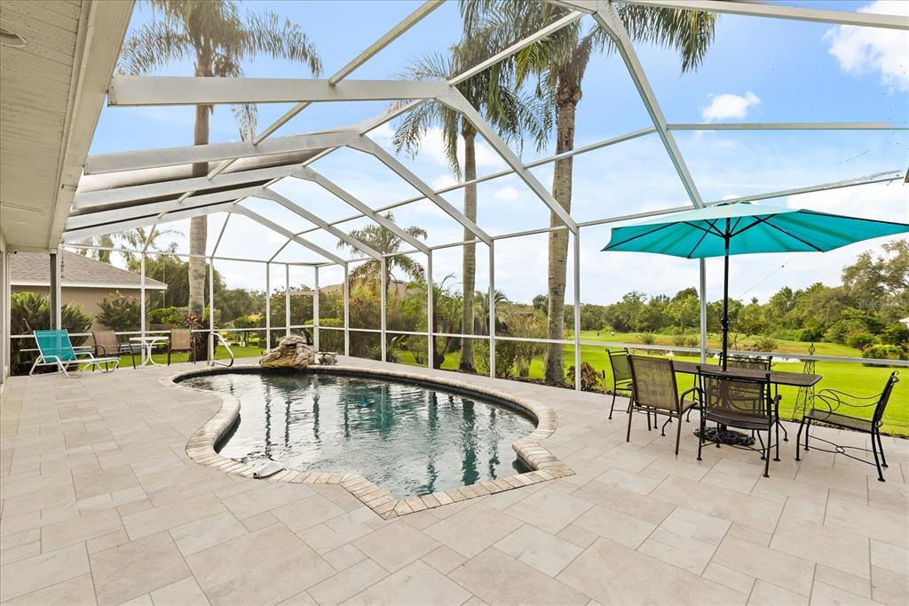 A screened-in patio features a swimming pool, stone pavers, and outdoor dining furniture — 7103 MONTREAL DRIVE, LAKELAND, FL