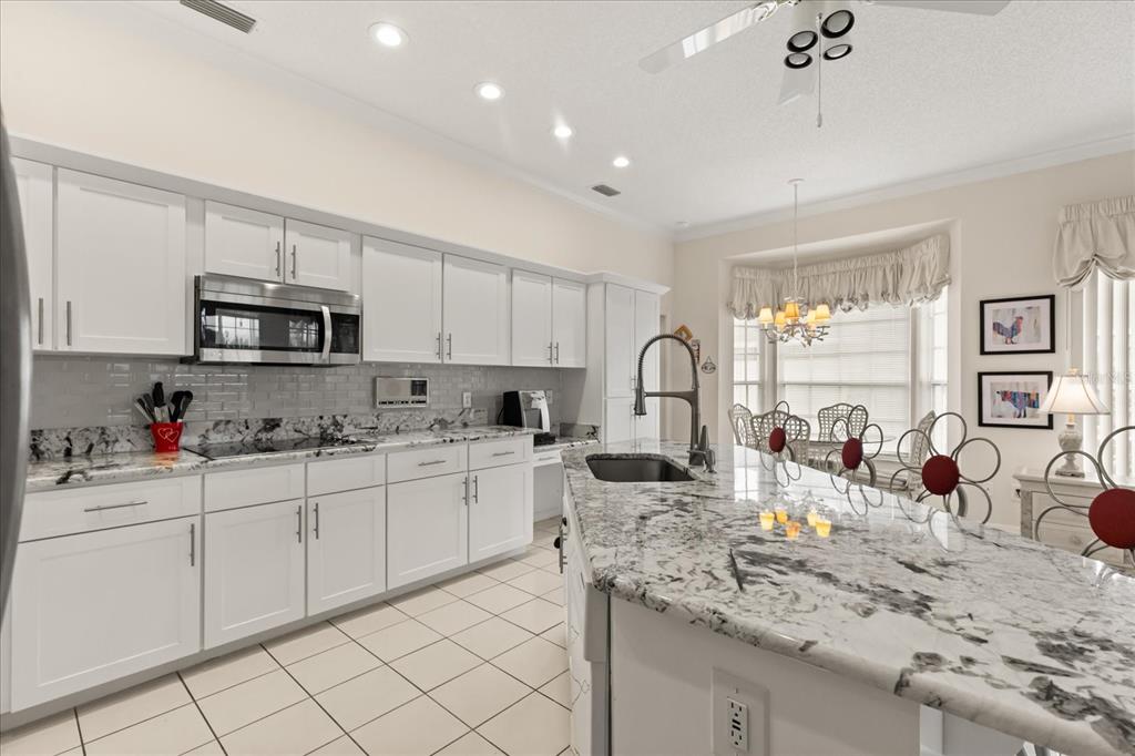 A kitchen features white cabinetry, granite countertops, a large island, and a breakfast nook area — 7103 MONTREAL DRIVE, LAKELAND, FL