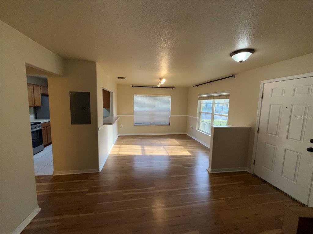 An interior view of a living room with wood-look flooring and a view into the kitchen — 37603 DALIHA TERRACE, ZEPHYRHILLS, FL