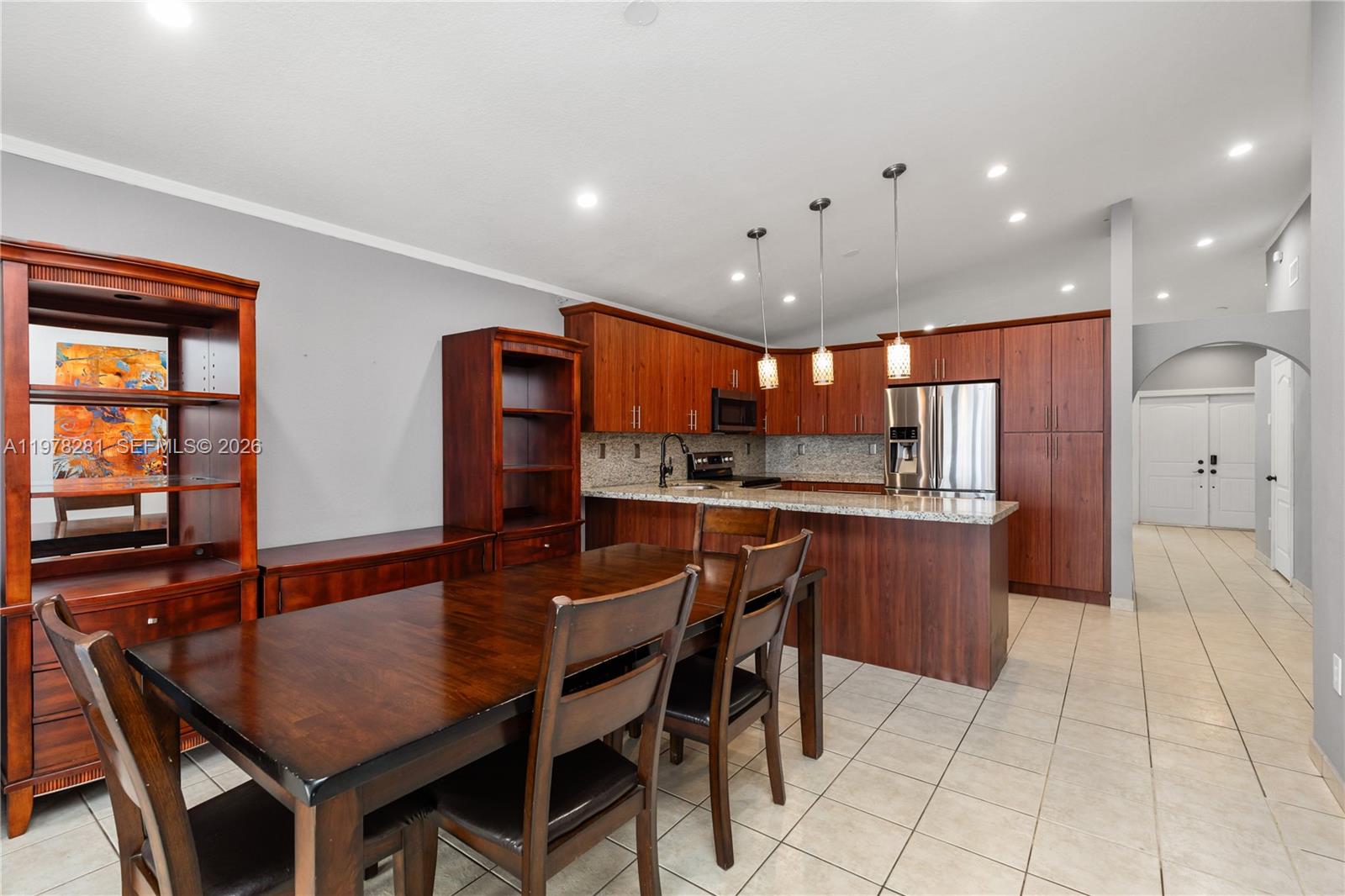 A kitchen with wood cabinets and granite countertops sits adjacent to a wooden dining set — 14358 SW 168th St, Miami FL 33177, MIAMI, FL