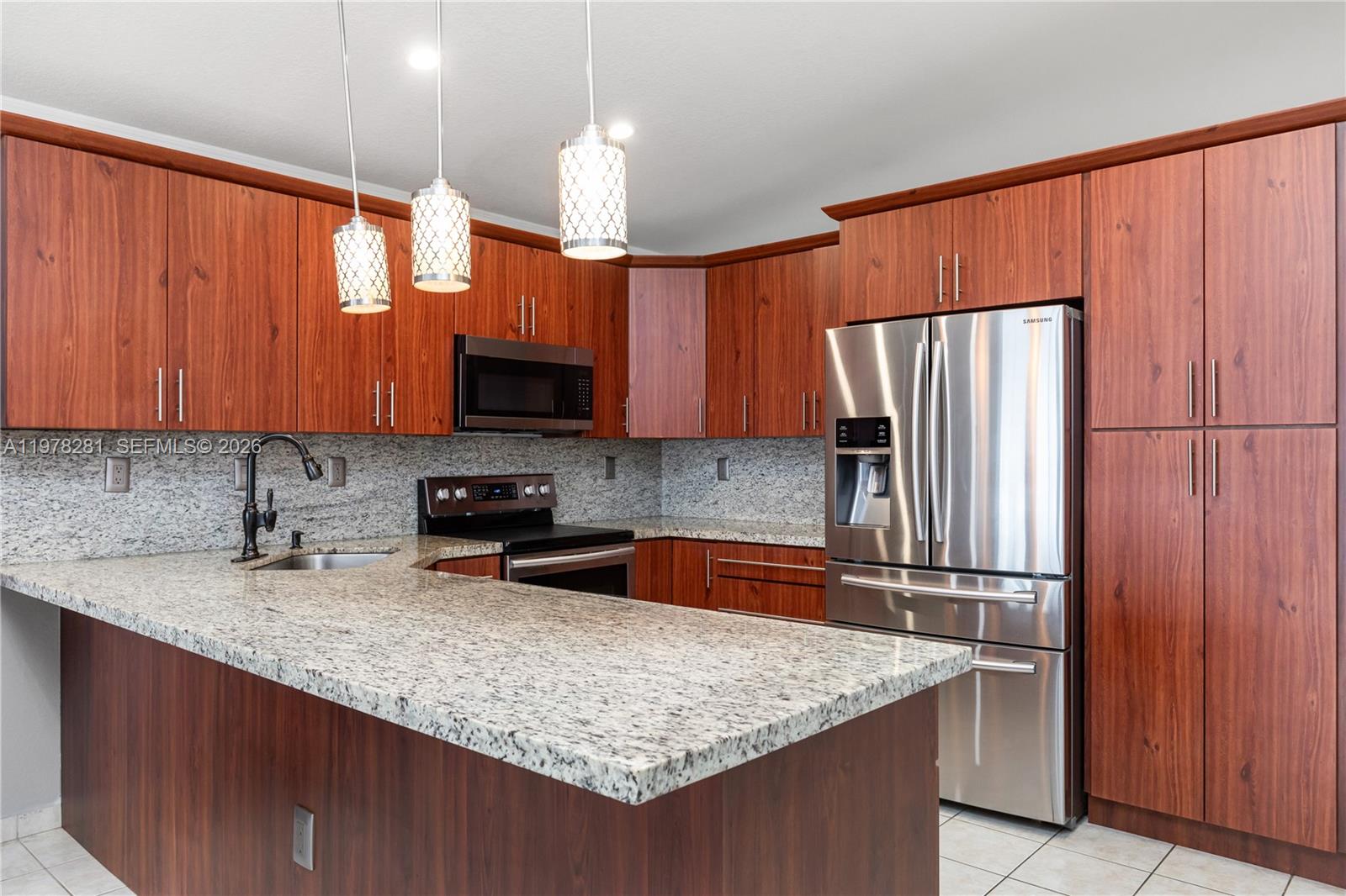 A kitchen features wood cabinets, granite countertops, stainless steel appliances, and three hanging pendant lights — 14358 SW 168th St, Miami FL 33177, MIAMI, FL