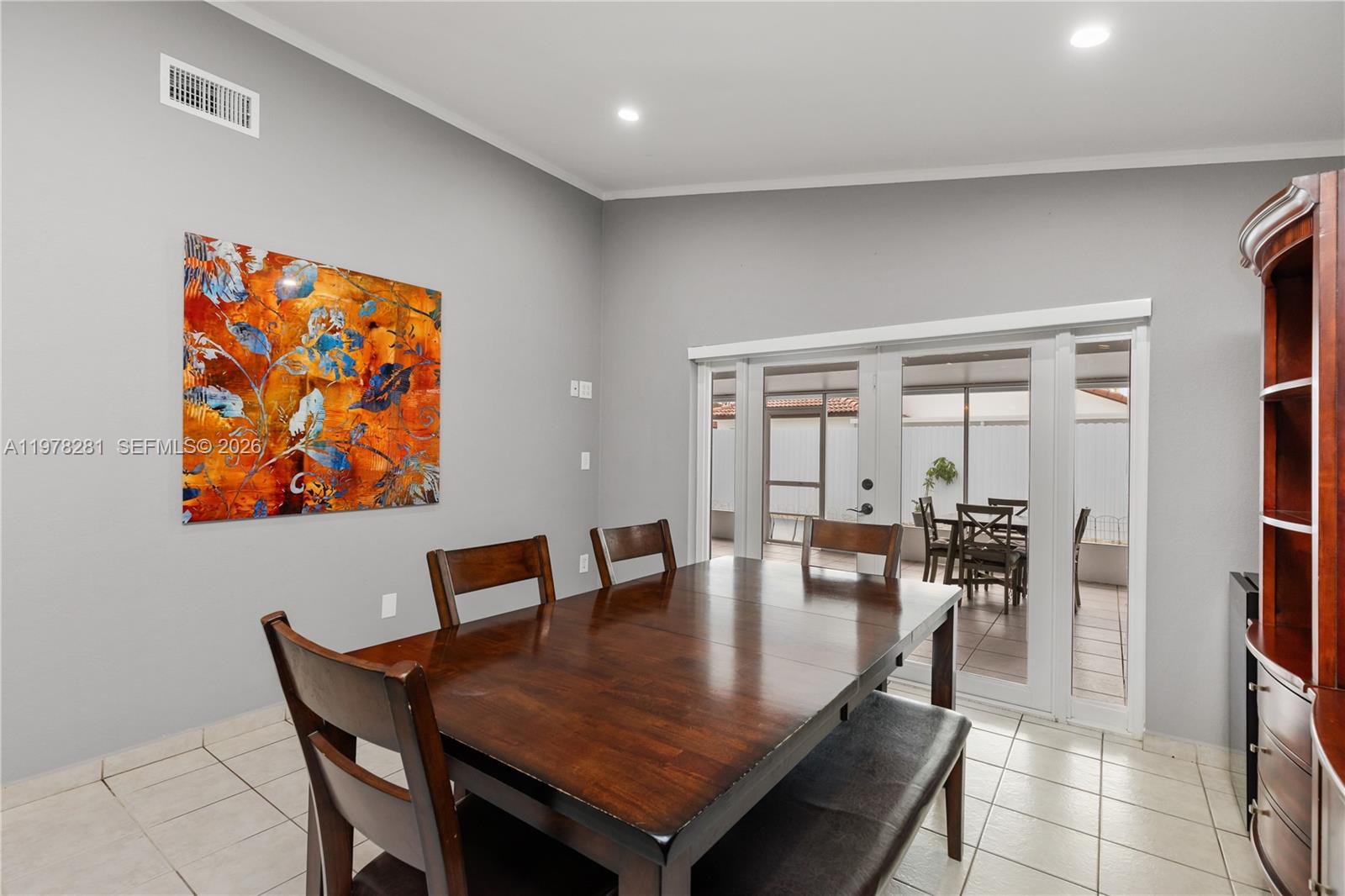 A dining room features a dark wood table, chairs, a bench, and glass patio doors — 14358 SW 168th St, Miami FL 33177, MIAMI, FL