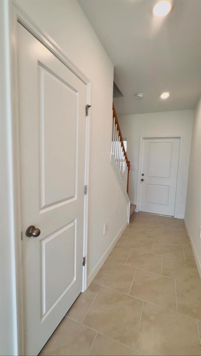 A hallway with tile flooring, a white door, and a staircase leading to an upper level — 4264 Cirella Court, FL 33917, FL