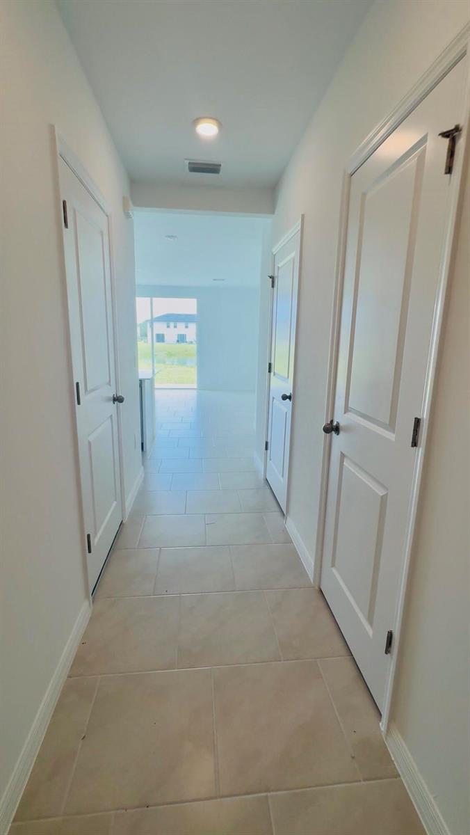 A hallway with light-colored tile flooring leads toward a bright, open living area — 4264 Cirella Court, FL 33917, FL