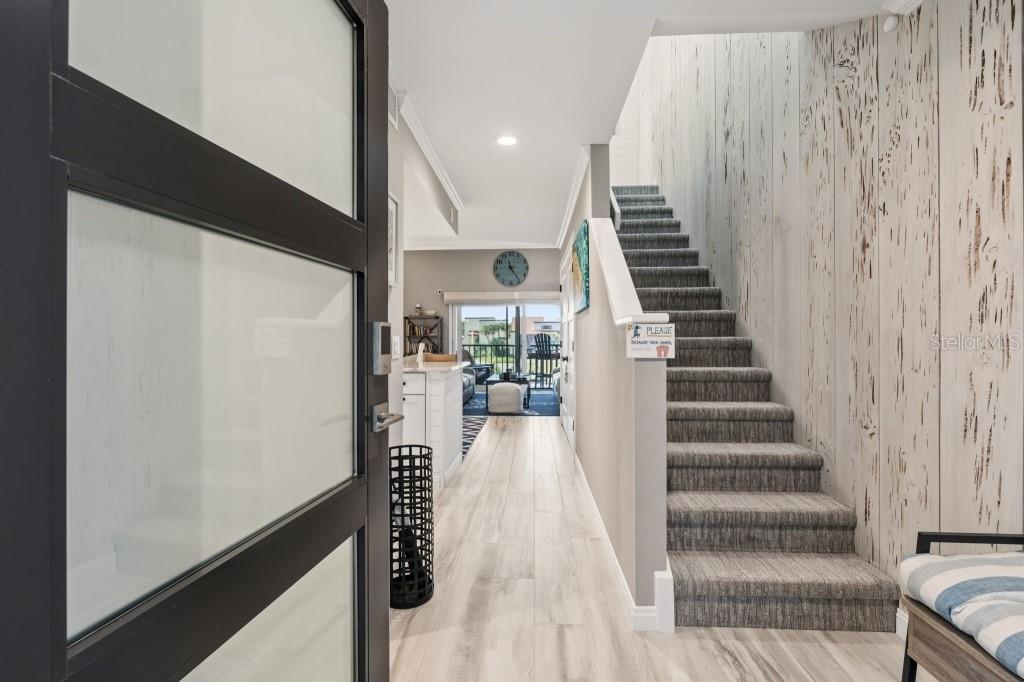 An entryway features a staircase with gray carpet, wood-look flooring, and a view toward outdoors — 2055 GULF OF MEXICO DRIVE UNIT G2-213, LONGBOAT KEY, FL