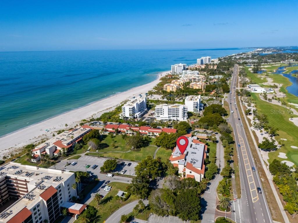 An aerial view shows a coastal resort with a red-roofed building marked by a pin — 2055 GULF OF MEXICO DRIVE UNIT G2-213, LONGBOAT KEY, FL