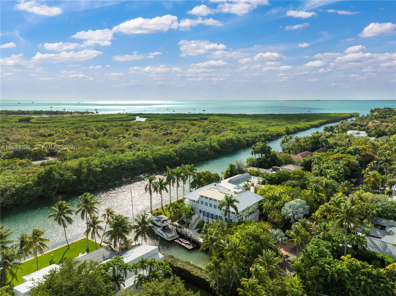 An aerial view shows a multi-story house with a boat dock along a canal — 100 Cape Florida Dr, Key Biscayne FL 33149, KEY BISCAYNE, FL