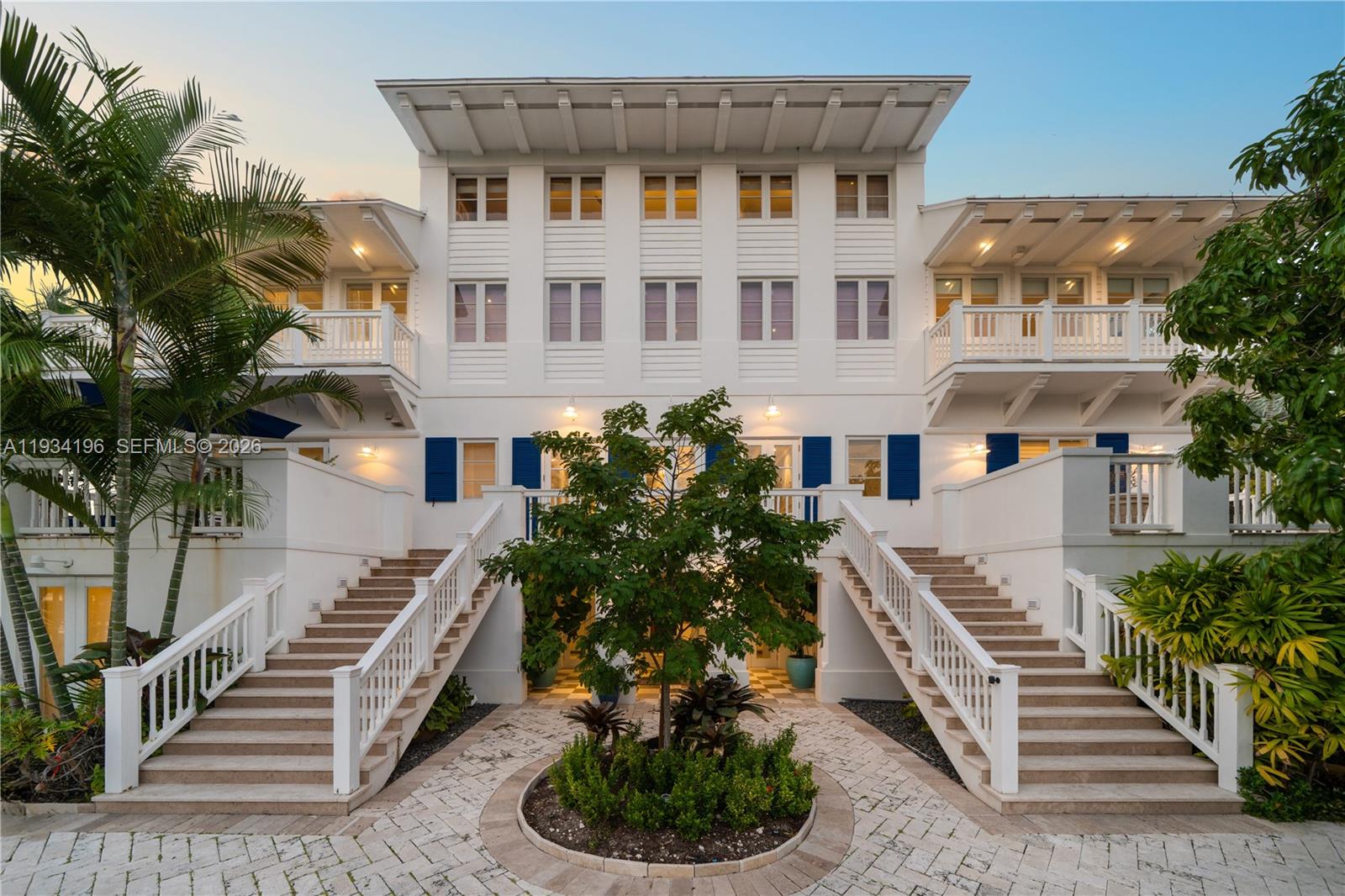 A three-story white house features symmetrical staircases leading to a central courtyard with a tree — 100 Cape Florida Dr, Key Biscayne FL 33149, KEY BISCAYNE, FL