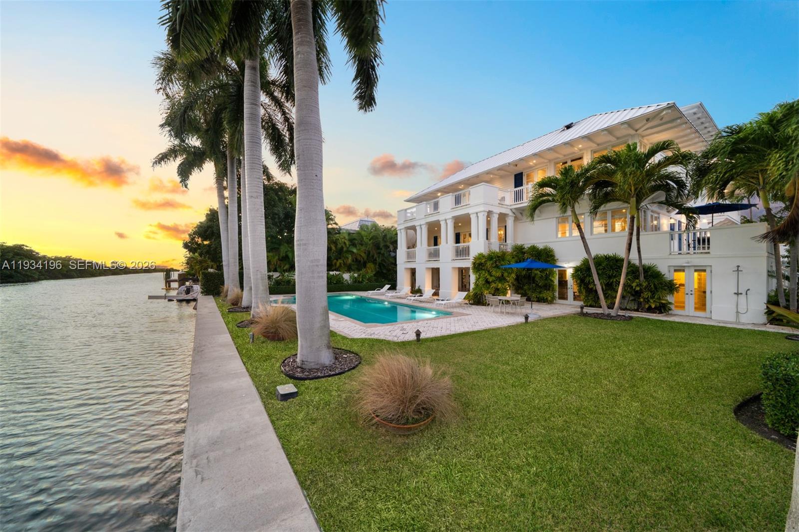 A multi-story white house with a pool and palm trees sits beside a canal — 100 Cape Florida Dr, Key Biscayne FL 33149, KEY BISCAYNE, FL