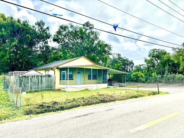 A single-story house with a light yellow exterior and a screened-in porch sits near a road — 904 SOUTHERN AVENUE, LAKELAND, FL