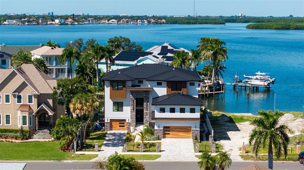An aerial view shows a modern two-story waterfront house with a black metal roof — 2121 BAYOU GRANDE BOULEVARD NE, ST PETERSBURG, FL