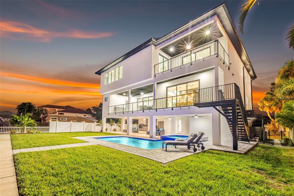 A three-story house with a pool, patio, and exterior staircase at sunset — 2121 BAYOU GRANDE BOULEVARD NE, ST PETERSBURG, FL