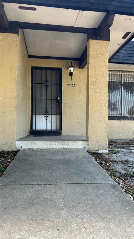 A concrete walkway leads to a front entrance with a black security door and lantern — 2235 SILVER PINES PLACE UNIT 401, ORLANDO, FL