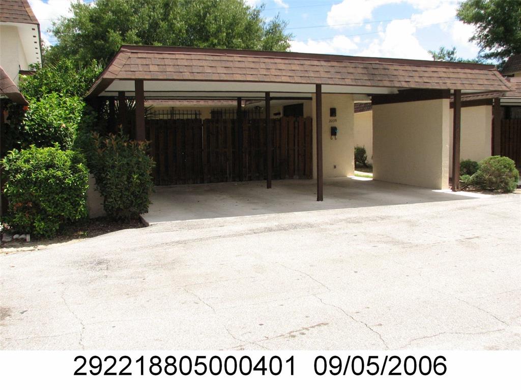 A covered carport with a shingled roof stands in front of a residential building — 2235 SILVER PINES PLACE UNIT 401, ORLANDO, FL