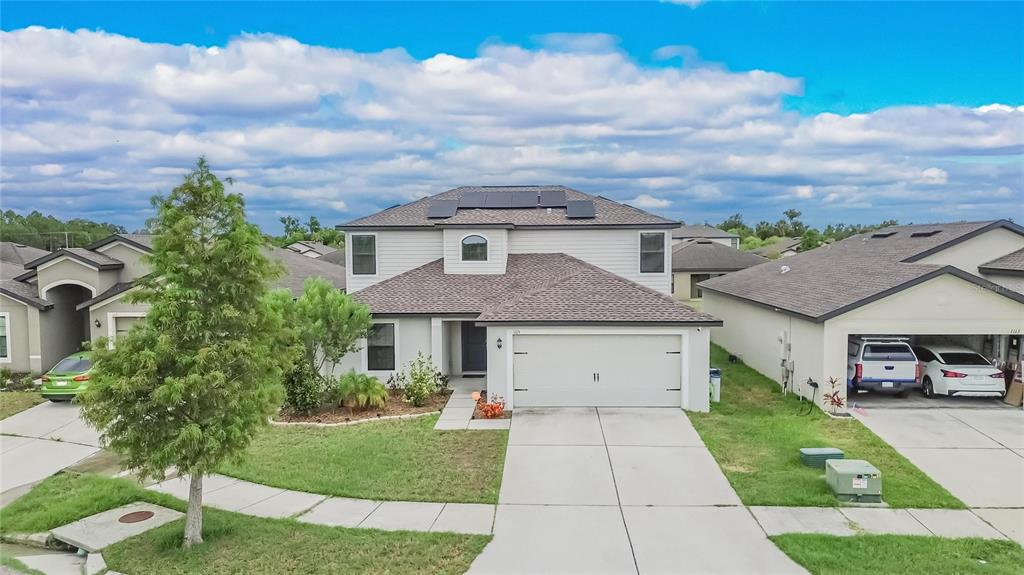 A two-story suburban house with a two-car garage and solar panels on the roof — 1115 WYNNMERE WALK AVENUE, RUSKIN, FL